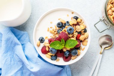 Beyaz masada taze böğürtlenli yoğurt ve tahıl gevreği. Sağlıklı atıştırmalık veya kahvaltı.