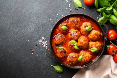 Beyaz masanın üstünde domates soslu köfte. Metin için boşluk ile kapat.