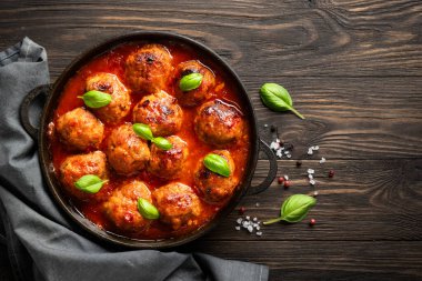 Ahşap masada fesleğen yapraklı domates soslu köfte. Üst görünüm.