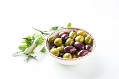 Zeytin karışımı ve beyaz arka planda taze zeytin dalları. Kapatın. Sağlıklı yiyecekler, geleneksel Akdeniz yemekleri.