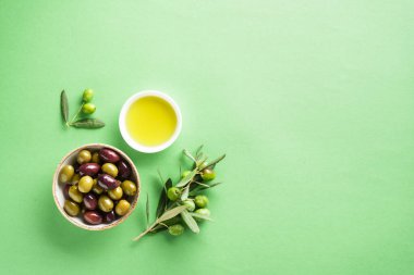 Yeşil arka planda zeytinyağı ve zeytin yağı şişesi karışımı. Dizayn için alanı olan düz resim.