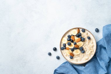 Sütlü, muzlu, fındıklı ve yaban mersinli yulaf lapası. Tasarım için alanı olan üst görünüm.
