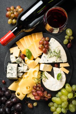 Peynir çeşitleri ya da peynir tabağı tahtada ve kırmızı şarap siyah arka planda. Üst görünüm.