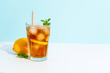 Limon ve buzlu buzlu çay. Renkli arka planda sert gölgeli yaz içeceği.