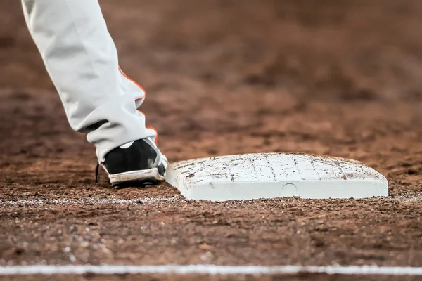 Baseballspieler mit Füßen, die die Bodenplatte berühren Stockbild