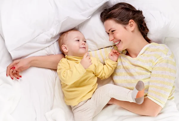 Madre jugando con el bebé en la cama — Stok fotoğraf