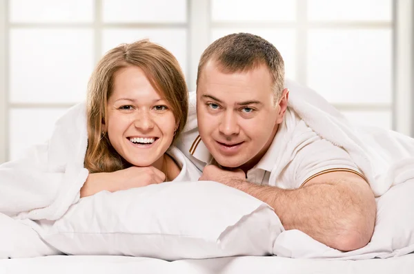 Par liggande i sängen leende — Stockfoto