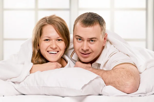 Casal deitado na cama sorrindo — Fotografia de Stock