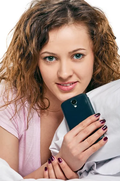 Mulher radiante com telefone deitado na cama — Fotografia de Stock