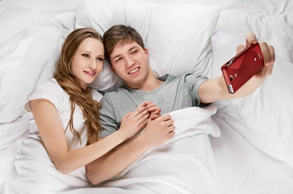 Couple au lit prenant une photo avec smartphone — Photo