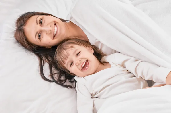 Mamma leker med dotter på sängen — Stockfoto