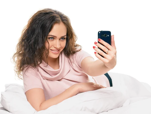 Femme rayonnante avec téléphone couché sur le lit — Photo