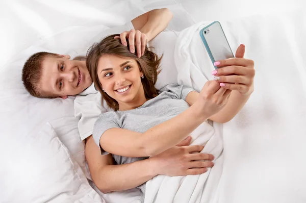 Par i sängen tar en bild med smartphone — Stockfoto