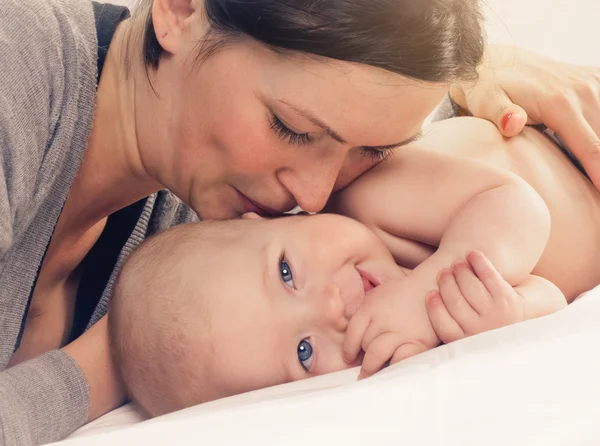 Mãe beijando bebê feliz na bochecha — Fotografia de Stock