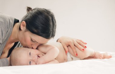 Mother kissing happy baby on cheek clipart