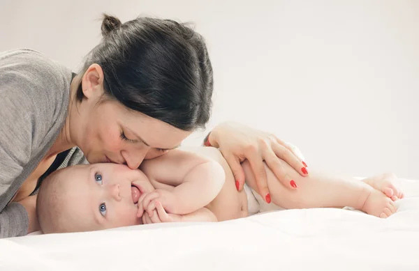 Mamma kysser happy baby på kinden — Stockfoto
