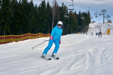 Genç aktif kadın kış dağlarında kayak yapıyor.