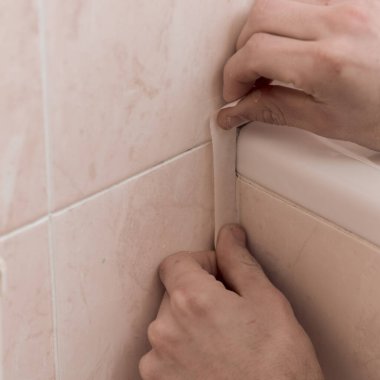 Banyodaki boruya yapışkan bant yapıştıran adama yaklaş.