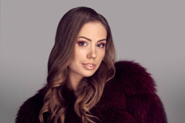 Stüdyoda poz veren zarif kürklü güzel esmer kadın model.