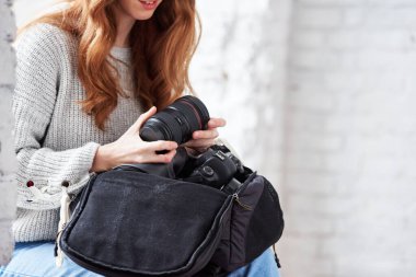 Elinde çantasıyla dijital kamera olan kadın fotoğrafçının yakın plan fotoğrafı.