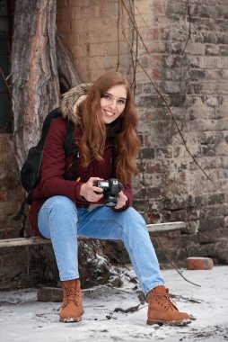 Dışarıda dijital kamerası olan gülümseyen genç kadın fotoğrafçı.