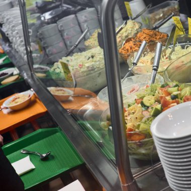 Kafedeki yemek kuyruğundaki farklı yemeklerin yakın plan fotoğrafı.