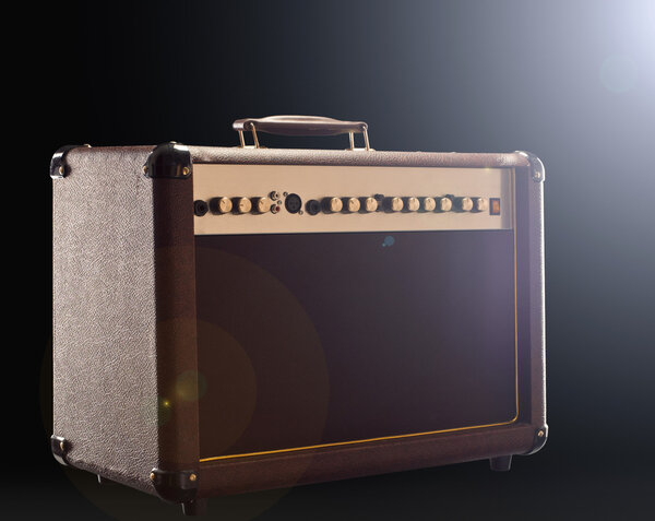 Acoustic guitar amplifier on the dark background with back light right