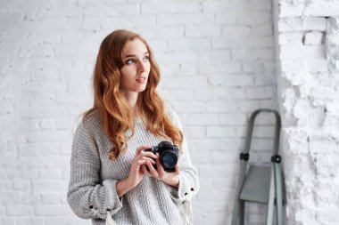 Beyaz stüdyoda modern fotoğraf makinesi olan genç ve güzel bir fotoğrafçının portresi.