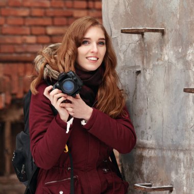 Gülümseyen mutlu kadın dijital kamerayla dışarıda fotoğraf çekiyor.