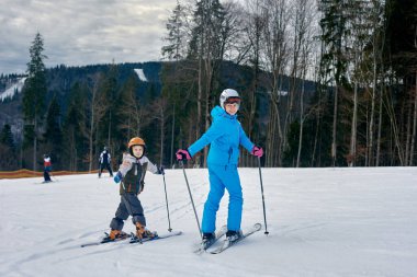 Anne ve oğlu kış dağlarında kayak tatilindeler.