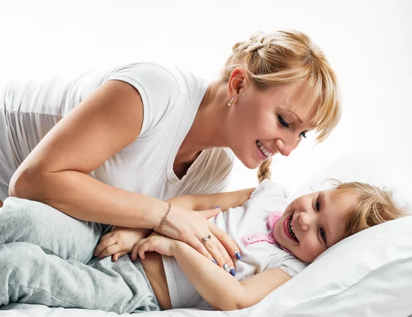 Kvinna och dotter liggande i sängen leende — Stockfoto