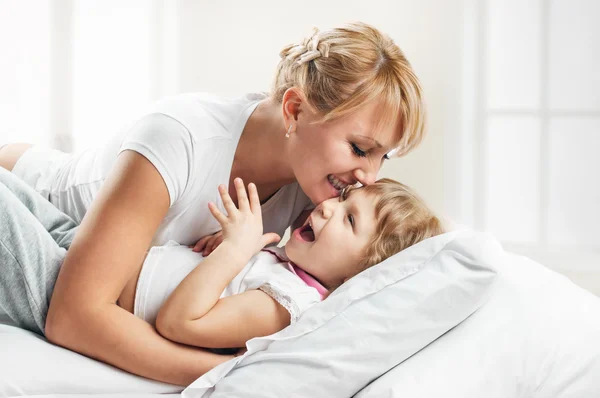 Žena a dcera leží v posteli s úsměvem — Stock fotografie