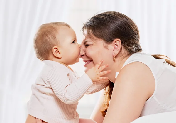 Kvinna och dotter spelar i sängen — Stockfoto