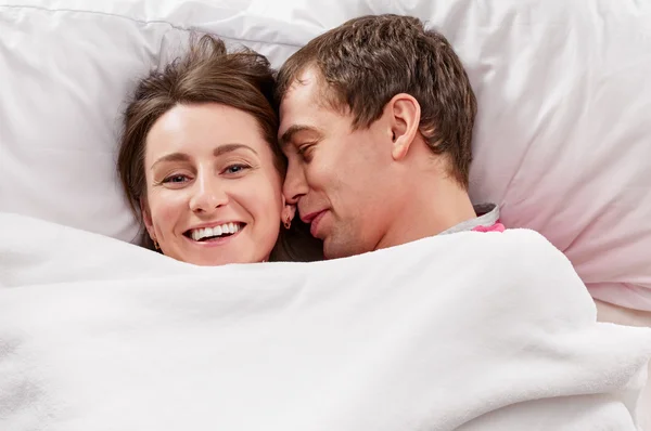 Pareja acostada en la cama sonriendo — Foto de Stock