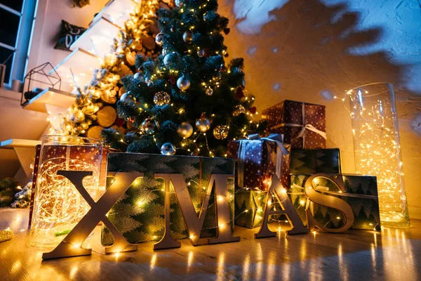 2021 yılının içinde mumlar, ampuller ve bokeh ile. Noel kutlaması için dekore edilmiş bir oda. Hediyeli Noel ağacı