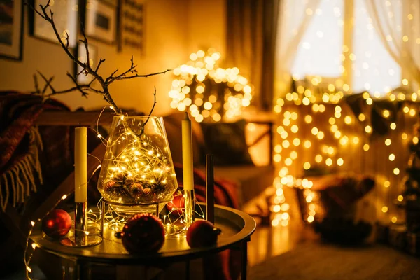 New Year 2021 interior with candles, bulbs and bokeh. Room decorated to christmas celebration. Christmas tree with presents