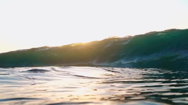 水中でのスローモーション大規模なターコイズバレル波は 晴れた夏の夜にカメラに侵入します 黄金の太陽の下での透き通った波の眺め海の波の上のシネマグラフ — ストック動画