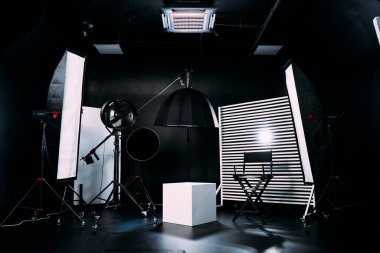 Kristal Beyaz oda siklonaması. Tam bir kara siklonama. Profesyonel ekipmanlı modern fotoğraf stüdyosu. Işık ekipmanlı boş fotoğraf stüdyosu. Yönetmen prodüksiyon koltuğuyla modern fotoğraf stüdyosunun içi..