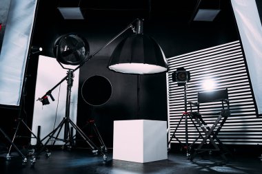 Kristal Beyaz oda siklonaması. Tam bir kara siklonama. Profesyonel ekipmanlı modern fotoğraf stüdyosu. Işık ekipmanlı boş fotoğraf stüdyosu. Yönetmen prodüksiyon koltuğuyla modern fotoğraf stüdyosunun içi..