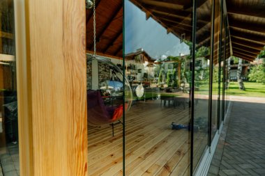 Balkonlu zarif ahşap ev terası. Banyo ve yatak odasının kapıları. Ahşap zeminli, mobilyalı ve muhteşem manzaralı geniş bir teras manzarası..