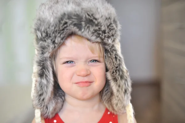 Baby girl with big blue eyes wearing a huge winter hat — Stock Photo, Image