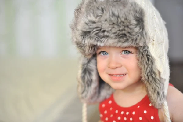 Baby girl with big blue eyes wearing a huge winter hat — Stock Photo, Image