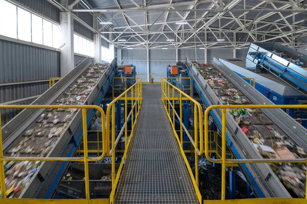 Waste sorting plant conveyors filled with various household waste.