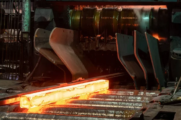 Red-hot metal billet on the roller table of a rolling mill