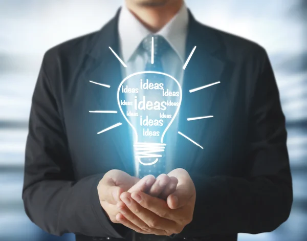Business person holding light bulb — Stock Photo, Image