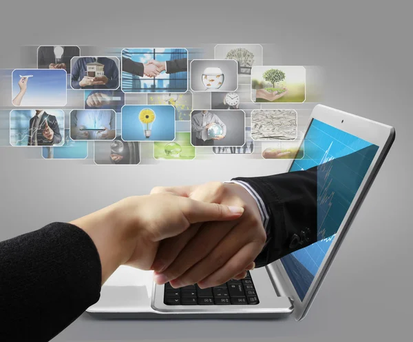 Strony firmy dotarcia z ekranu laptopa uścisnąć dłoń — Zdjęcie stockowe
