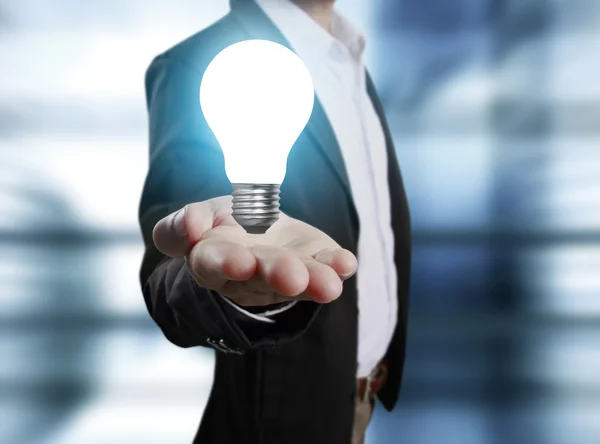 Business person holding light bulb — Stock Photo, Image