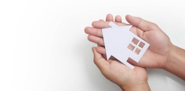 Kağıt ev, aile evi ve sigorta konseptini koruyan eller.