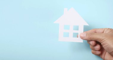 Kağıt ev, aile evi ve sigorta konseptini koruyan eller.