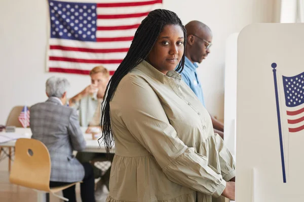 サイドビューポートレートの若いアフリカ系アメリカ人女性の投票ブースに立って カメラを見て スペースをコピー — ストック写真